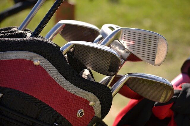 Image of a bunch of golf clubs in a golf bag in a golf course. Golf Swing Mistake: Picking The Wrong Club Type.
