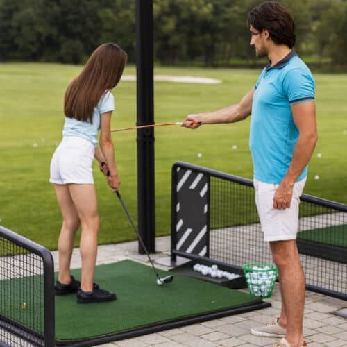 A beginner golfer being coached for her posture and golfing stance