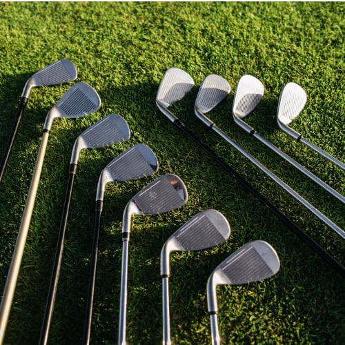 Eleven golf clubs placed on top of the grass of a golf course