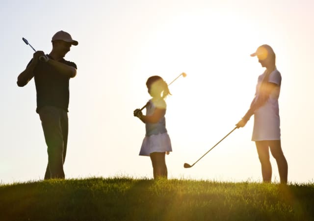 A male, female, and junior golfers' silhouette on a golf course