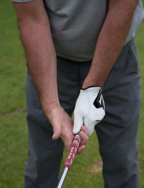 A golfer showing how he grips a golf club