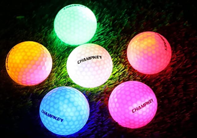 Six Champkey Premium Glow Golf Balls in different colored glows on top of a golf hitting mat