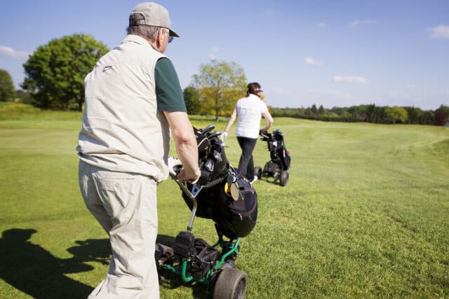 Golf couple walking on fairway with bags