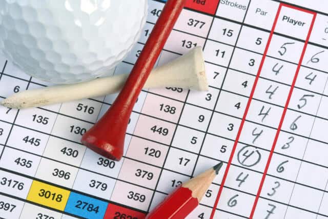 A golf ball, two golf tees, and a pencil on top of a golf scorecard