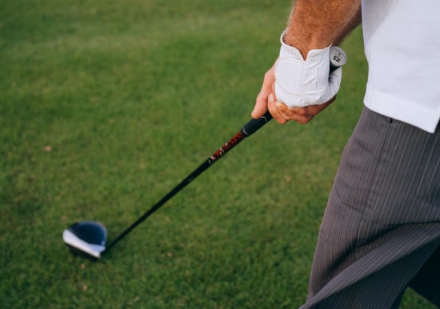 A golfer holding a hybrid golf club preparing to swing on a golf course