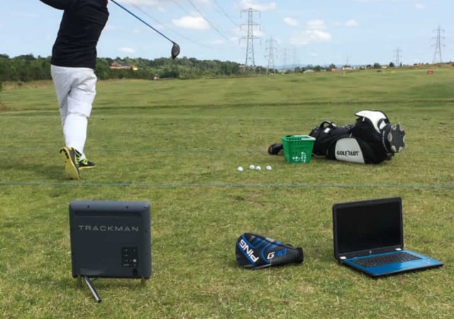 golf simulator tracking technologies like photometric, radar or doppler, and infrared technology laptop and other golfing equipment on the golf course with a golfer completing a golf swing
