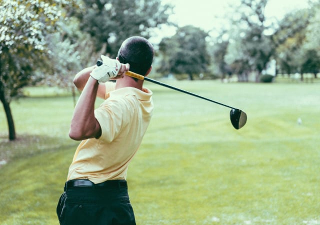 A golfer completing his swing on a golf course