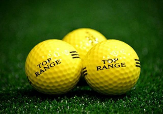 Three yellow range practice balls on green faux grass