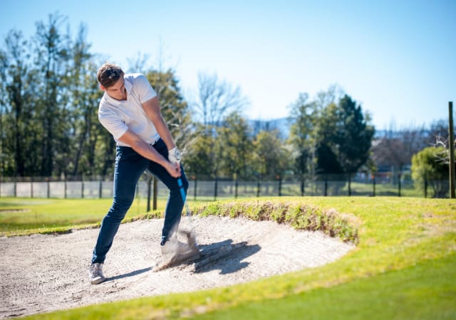 A golfer in the sand pit of a golfer making a bunker shot