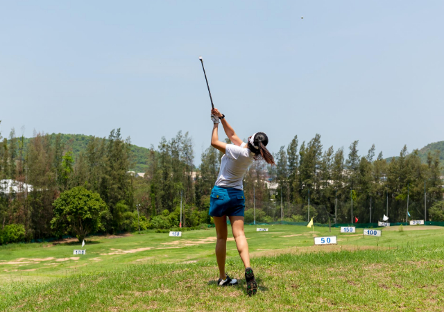 A female golfer completing a swing on the golf course.