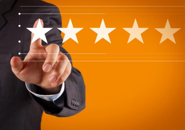 A man in a suit click on one of the five stars on orange background