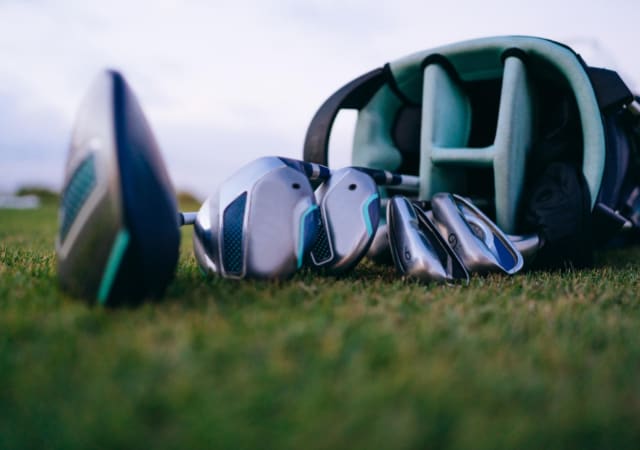 Hybrid golf clubs laid on the golf course with the golf bag