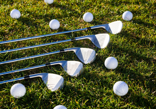Five iron golf clubs on the golf course with golf balls surrounding them