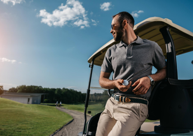 Golfer leaning on a golf cart on the golf course