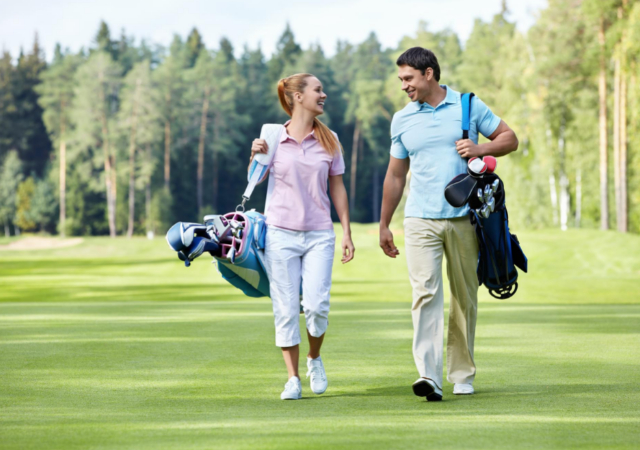 Male and female golfers carrying their golf bags on the golf course