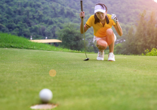 A female golfer watching the golf ball to fall into the hole in a golf course