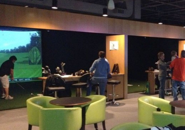 Indoor commercial golf simulator setups for business with tables and chairs in the surrounding