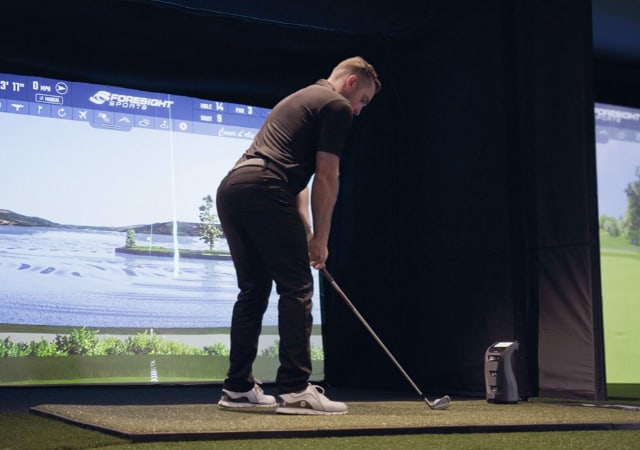 A golfer using a Foresight GC3 Launch monitor on a golf simulator setup