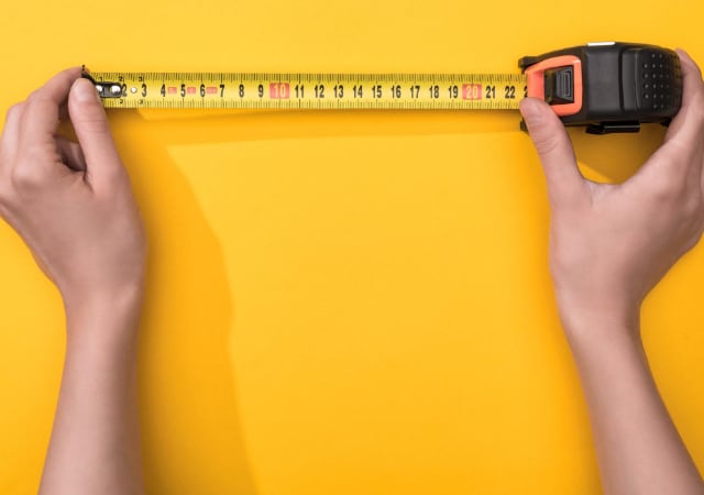 A person holding a meter on a yellow surface
