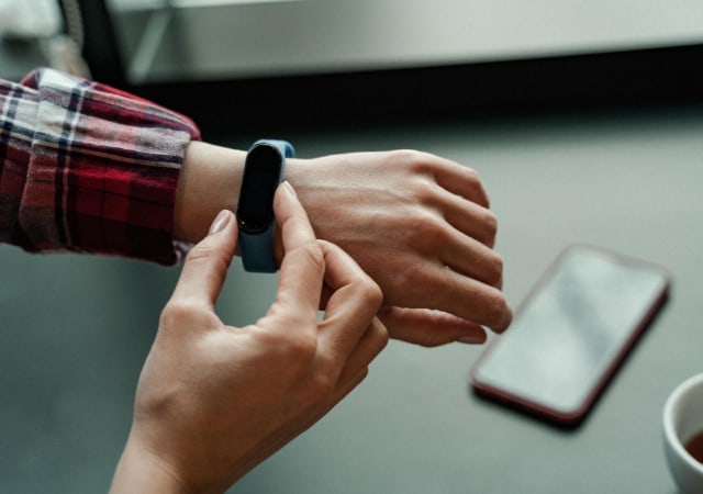 A person wearing a smart watch with a smart phone on the table